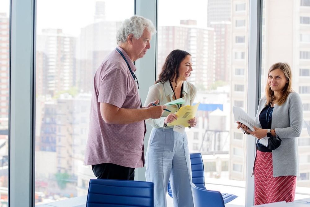 Diverse group of business professionals networking and chatting during a break in a bright office hallway.
