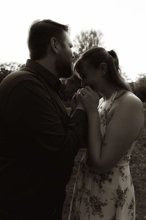 Black and white portrait of couple in intimate embrace against natural backdrop.