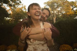 Joyful couple laughing together during sunset photoshoot with fall foliage.
