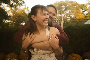 Happy couple embracing outdoors with autumn colors in background.