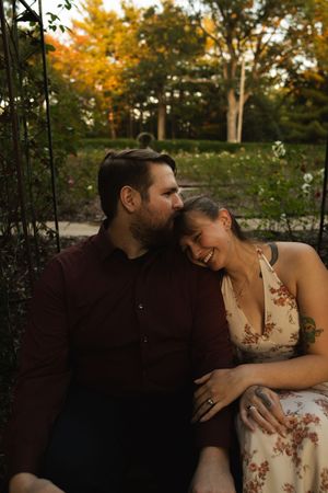 A romantic autumn photoshoot featuring a couple in casual attire surrounded by fall foliage.