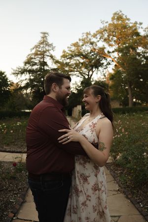 A playful moment captured between a couple on a garden path surrounded by fall foliage.
