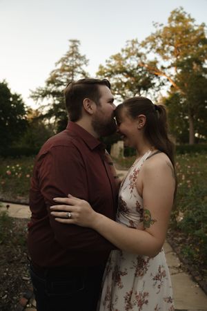 An intimate moment shared between a couple during a sunset photoshoot in a garden setting.