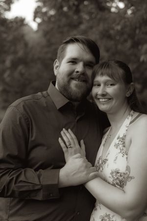 A black and white portrait of a couple showing their engagement ring.