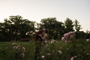 A couple embraces in a rose garden at sunset creating a romantic silhouette.