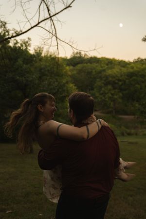 Couple dancing together in a field during golden hour.