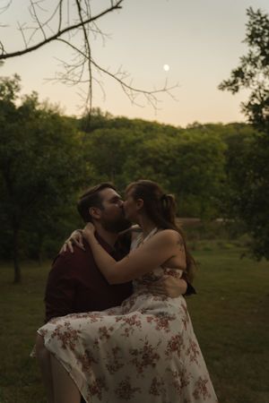 Intimate moment between couple during sunset photoshoot in nature.