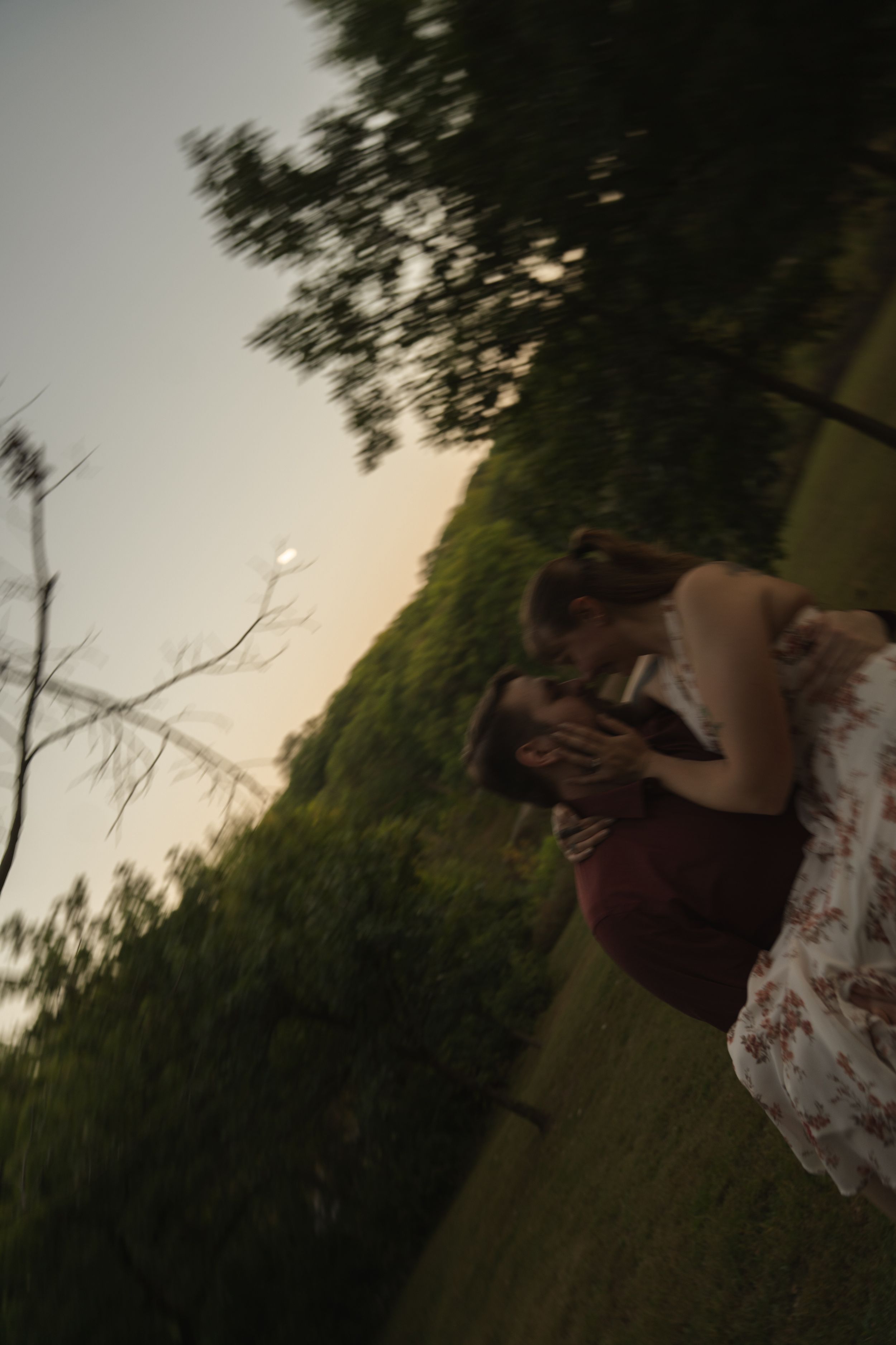Romantic couple embracing in a scenic outdoor setting during golden hour sunset.