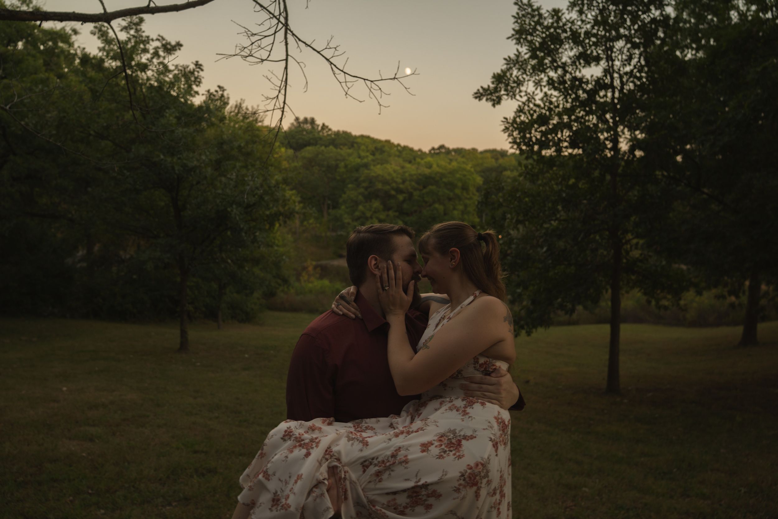 Silhouettes of a couple embracing in a serene field at sunset.