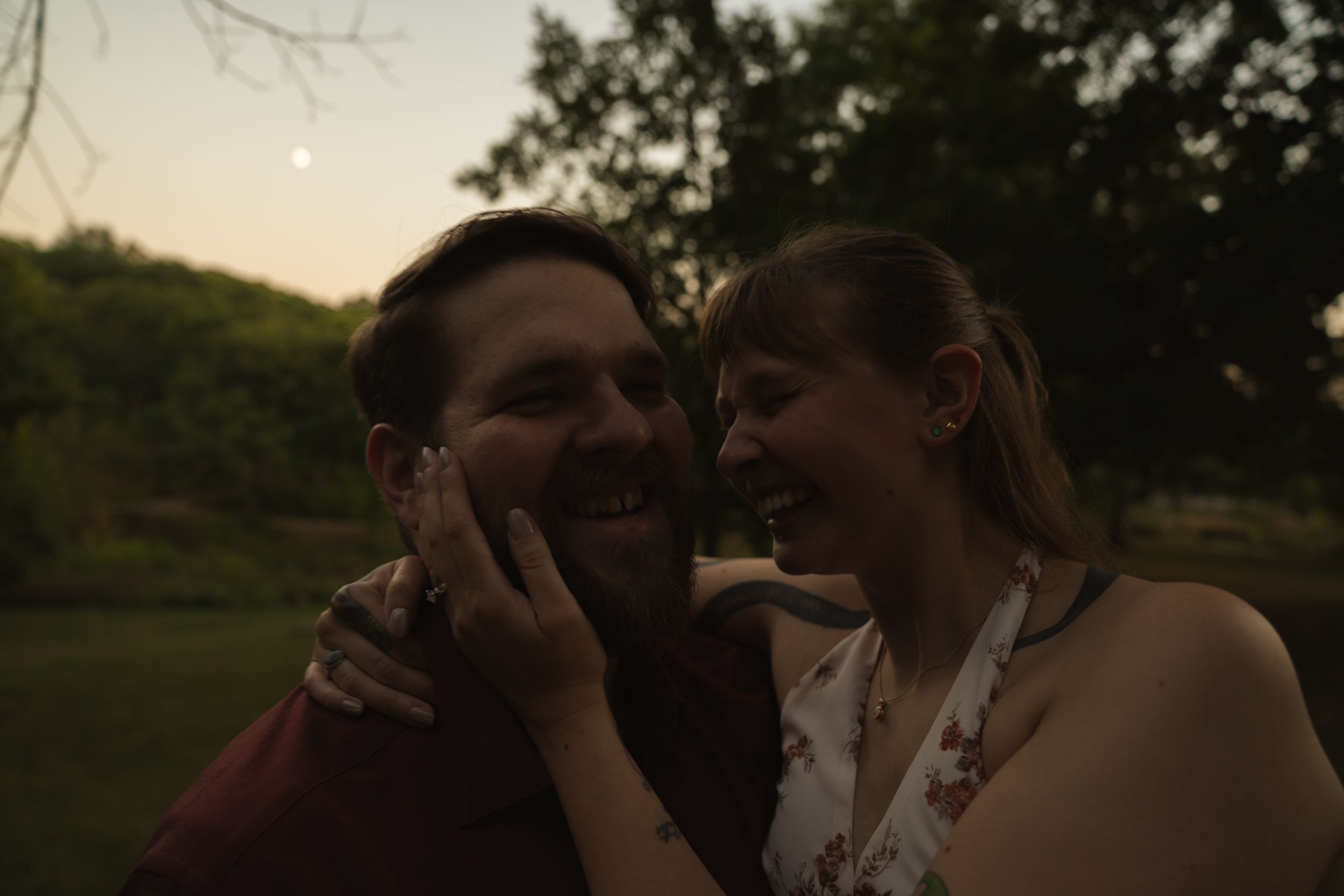 Tender embrace photographed against sunset sky and trees.