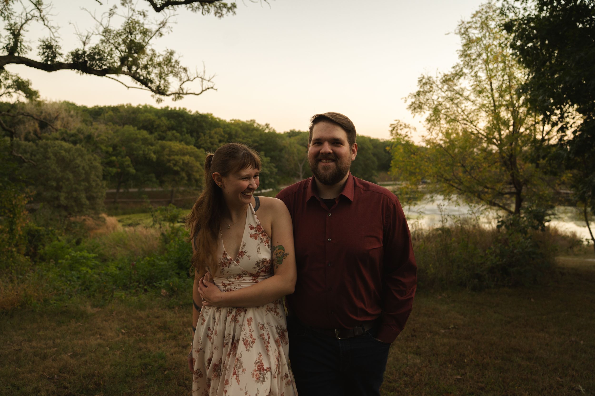 Romantic couple shares tender moments during golden hour photoshoot in a natural outdoor setting.