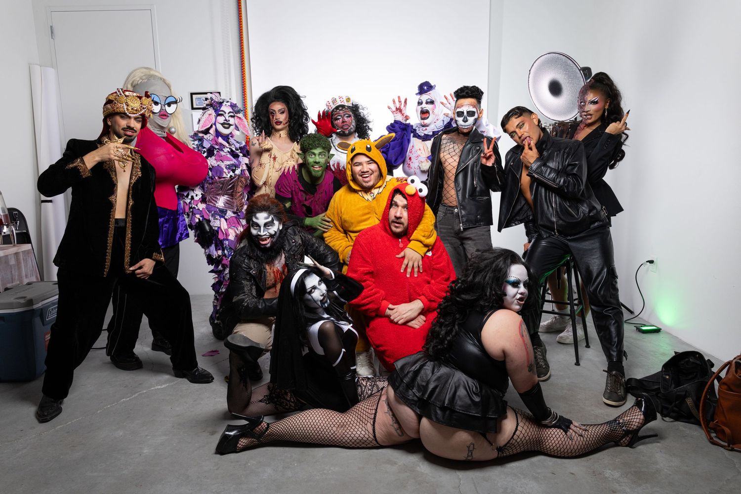 Cosplayers in colorful costumes pose together at a convention in a fun group photo session.