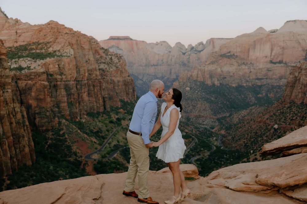 A romantic couple shares intimate moments against the stunning red rock formations of a desert canyon.