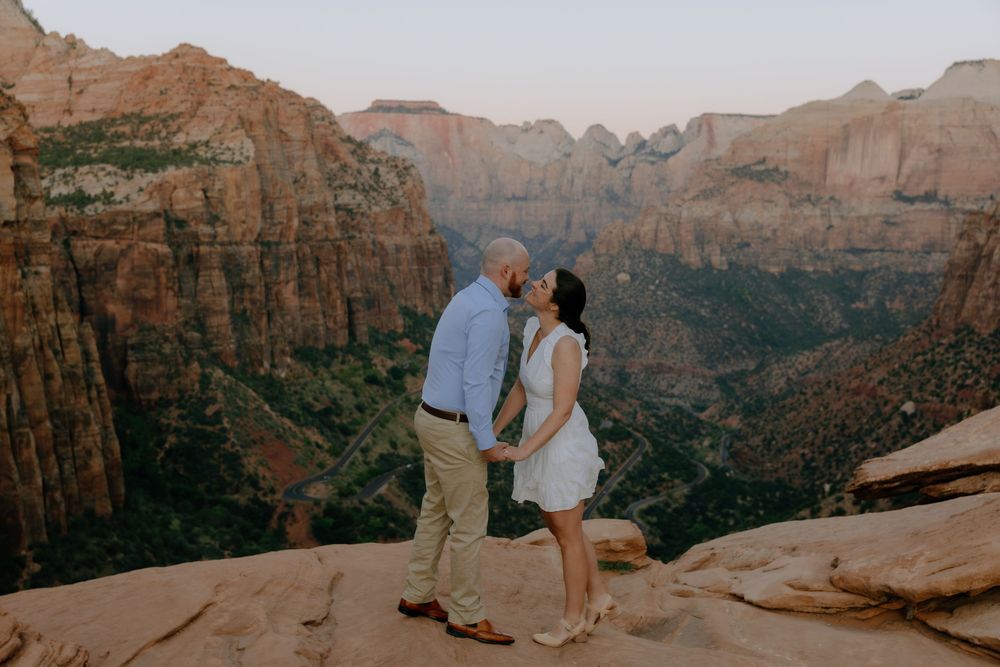 Scenic engagement photography session at sunset overlooking majestic red rock canyons and cliffs.