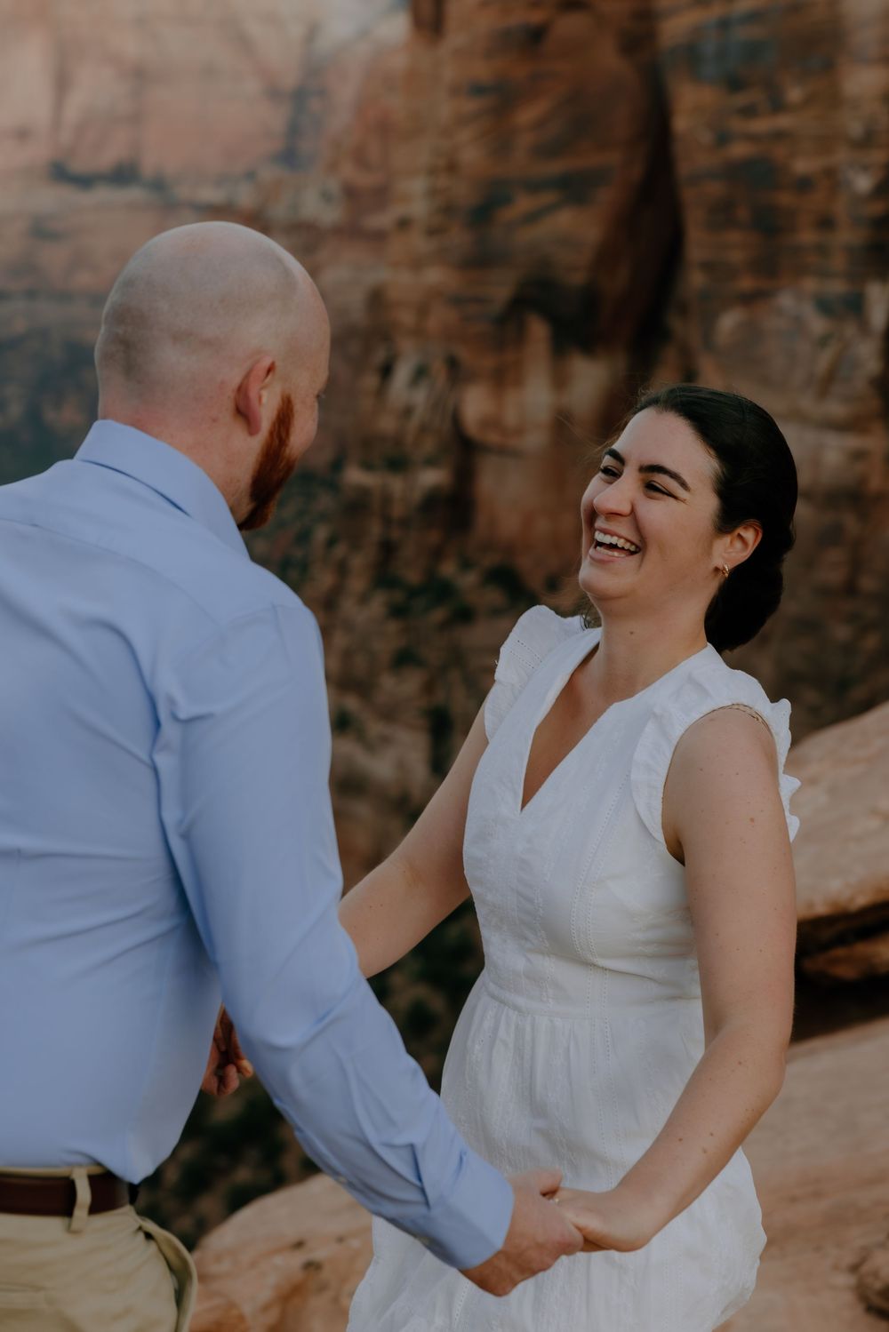 A couple shares intimate moments against a rustic stone wall backdrop during a photo session.
