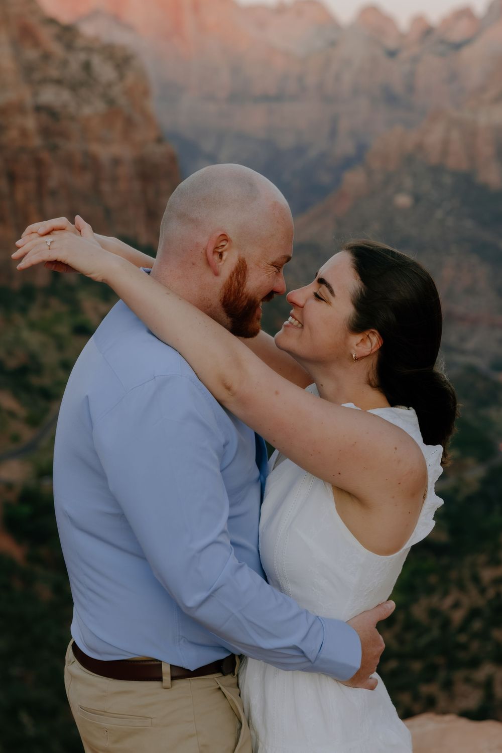 A romantic couple embraces against the backdrop of majestic red rock canyon cliffs during sunset.