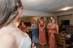 Group wearing coordinated dresses preparing in a rustic-styled room.