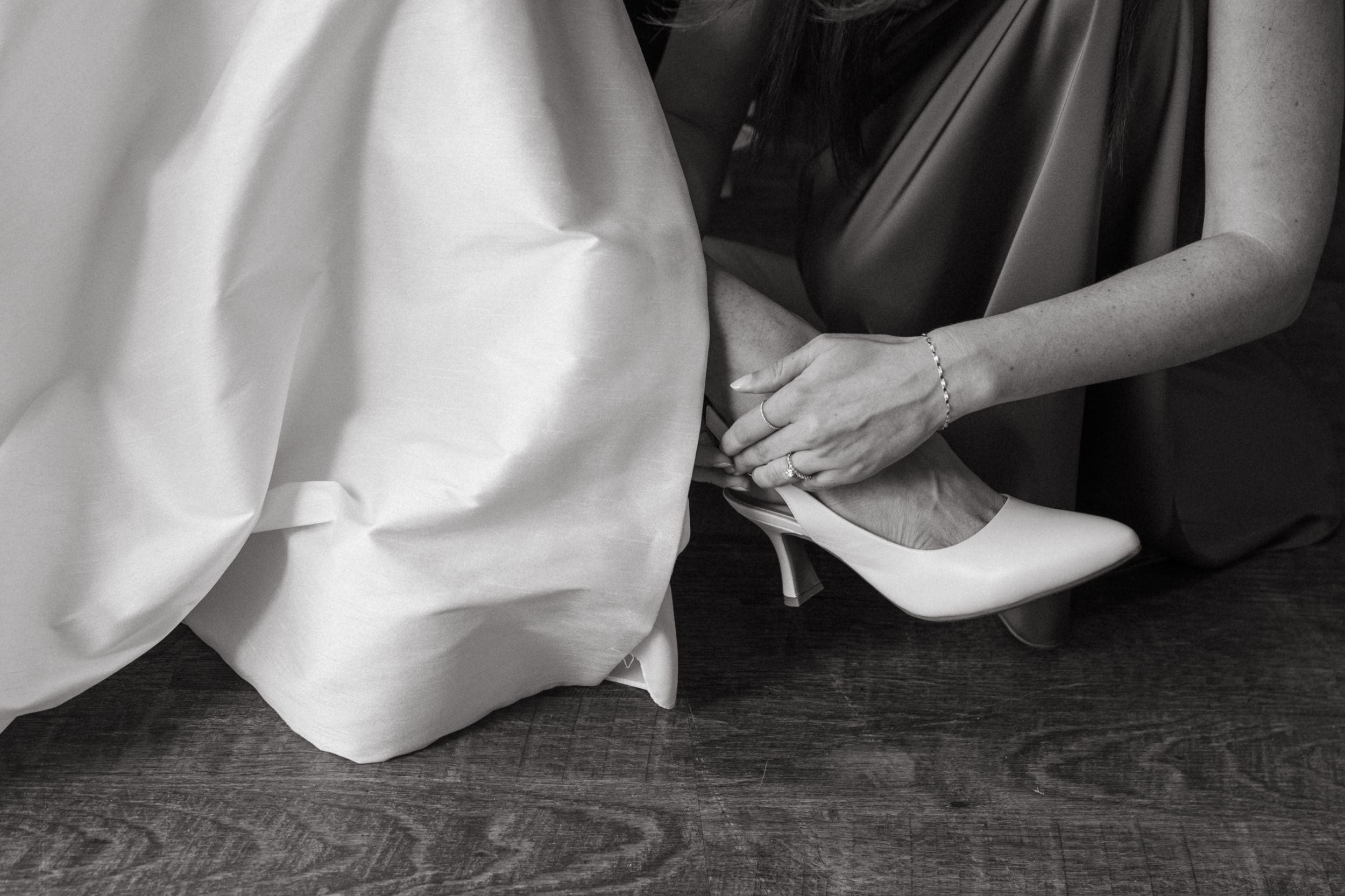 Sequential black and white images showing someone adjusting footwear on a hardwood floor.