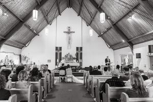 Interior view of a traditional church sanctuary with wooden pews and vaulted ceiling in black and white.