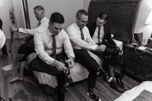 A black and white photo shows a person adjusting the laces on dress shoes while seated.