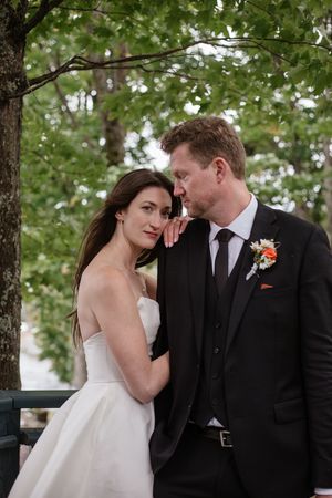 Intimate wedding portrait showing tender moments between newlyweds against a natural backdrop.