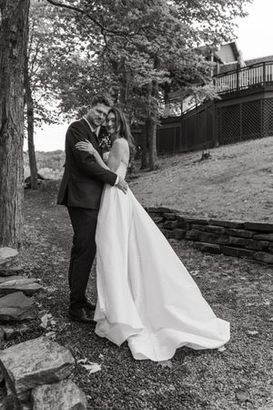 Black and white wedding photos showing romantic poses on a hillside with stone steps and trees.