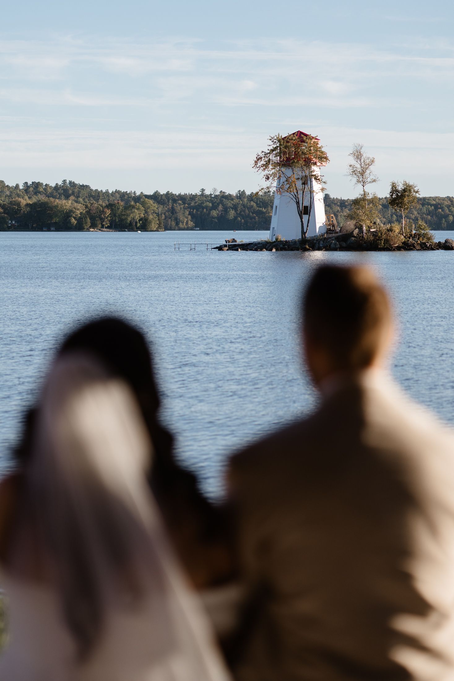Scenic lakeside view with a white lighthouse visible on a distant shore.