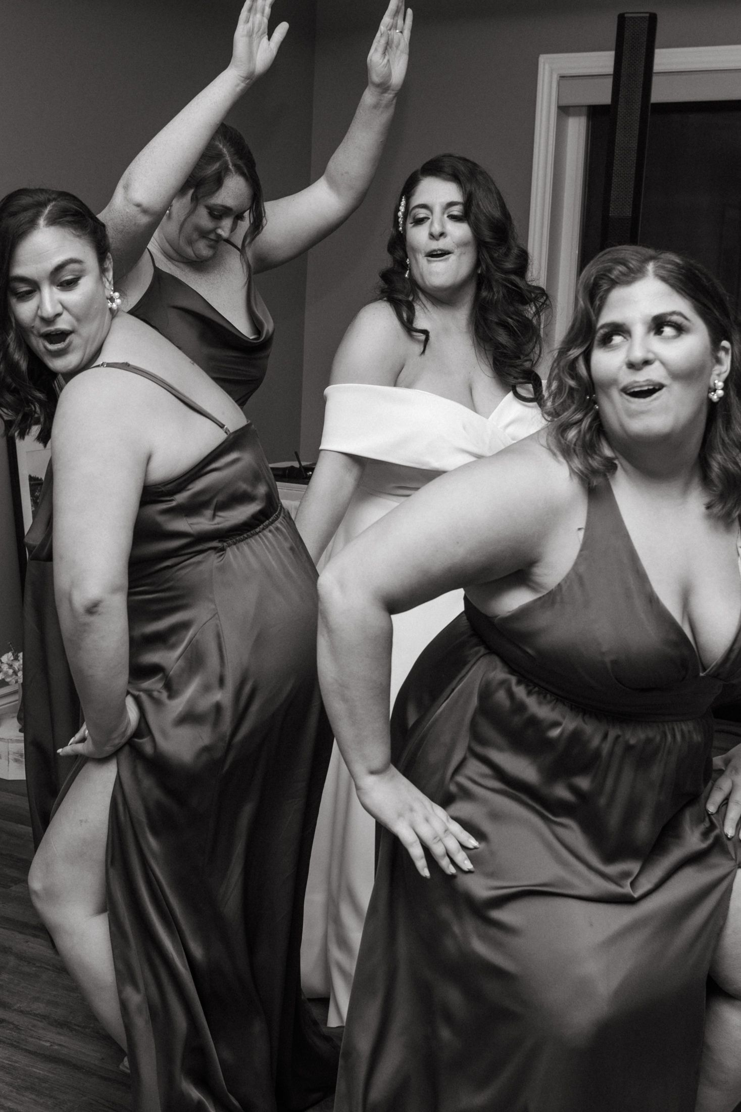 Black and white photo of people dancing and celebrating at a party in formal attire.