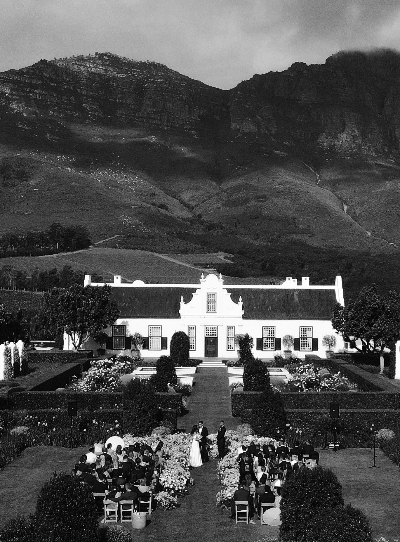 Historic black and white photos showing white colonial-style buildings nestled against dramatic mountain landscapes.