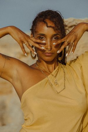 A person in a beige top poses expressively in a sequence of connected photos against a warm-toned background.