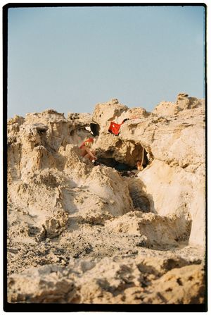 Distant figure visible atop limestone cliff formation against clear sky.