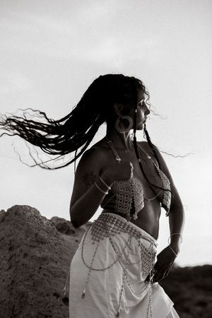 Dramatic black and white portrait with flowing dress and hair movement against natural backdrop.