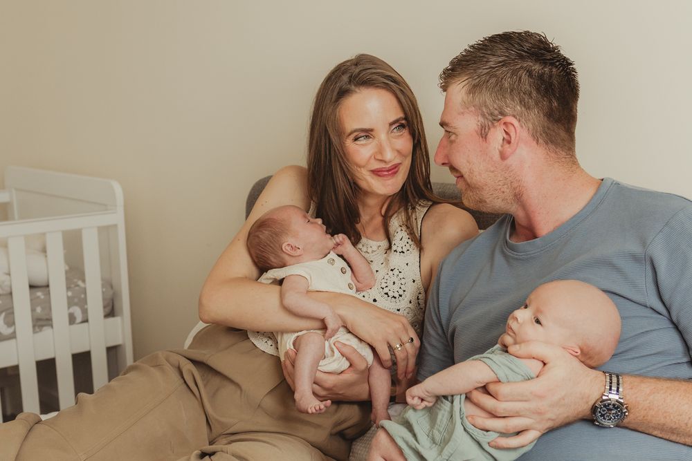 A tender family moment as parents snuggle with their newborn baby on a cozy bed.