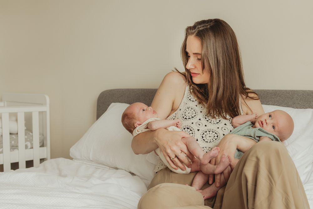 Parents sharing intimate bonding moments with their newborn baby in a bright bedroom setting.