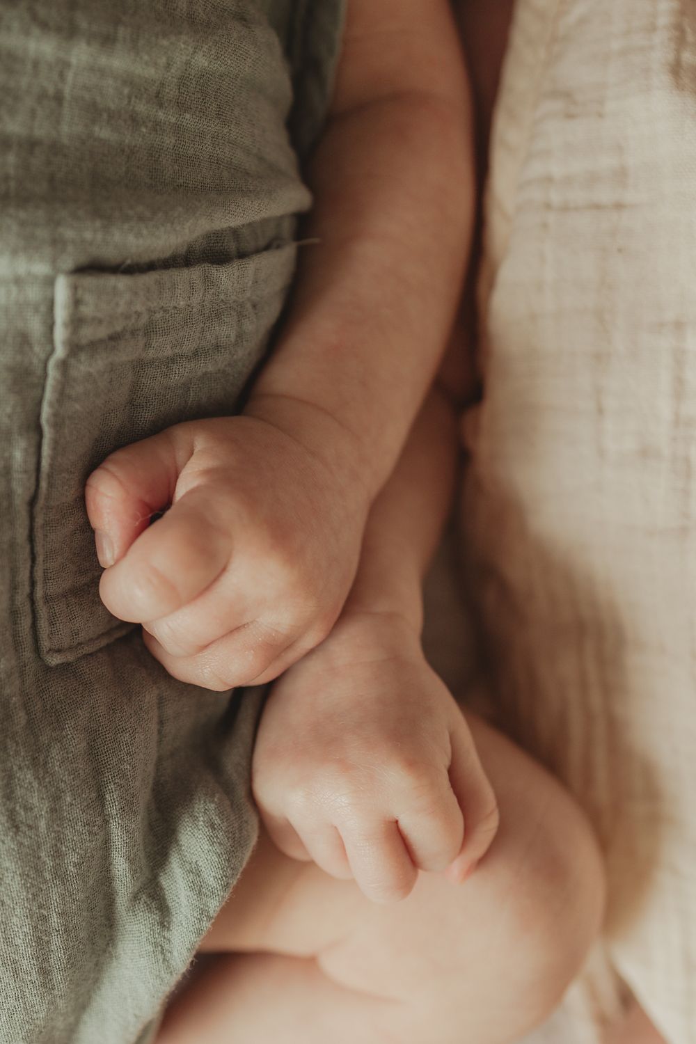Artistic close-up shots of baby hands against textured linen fabric.