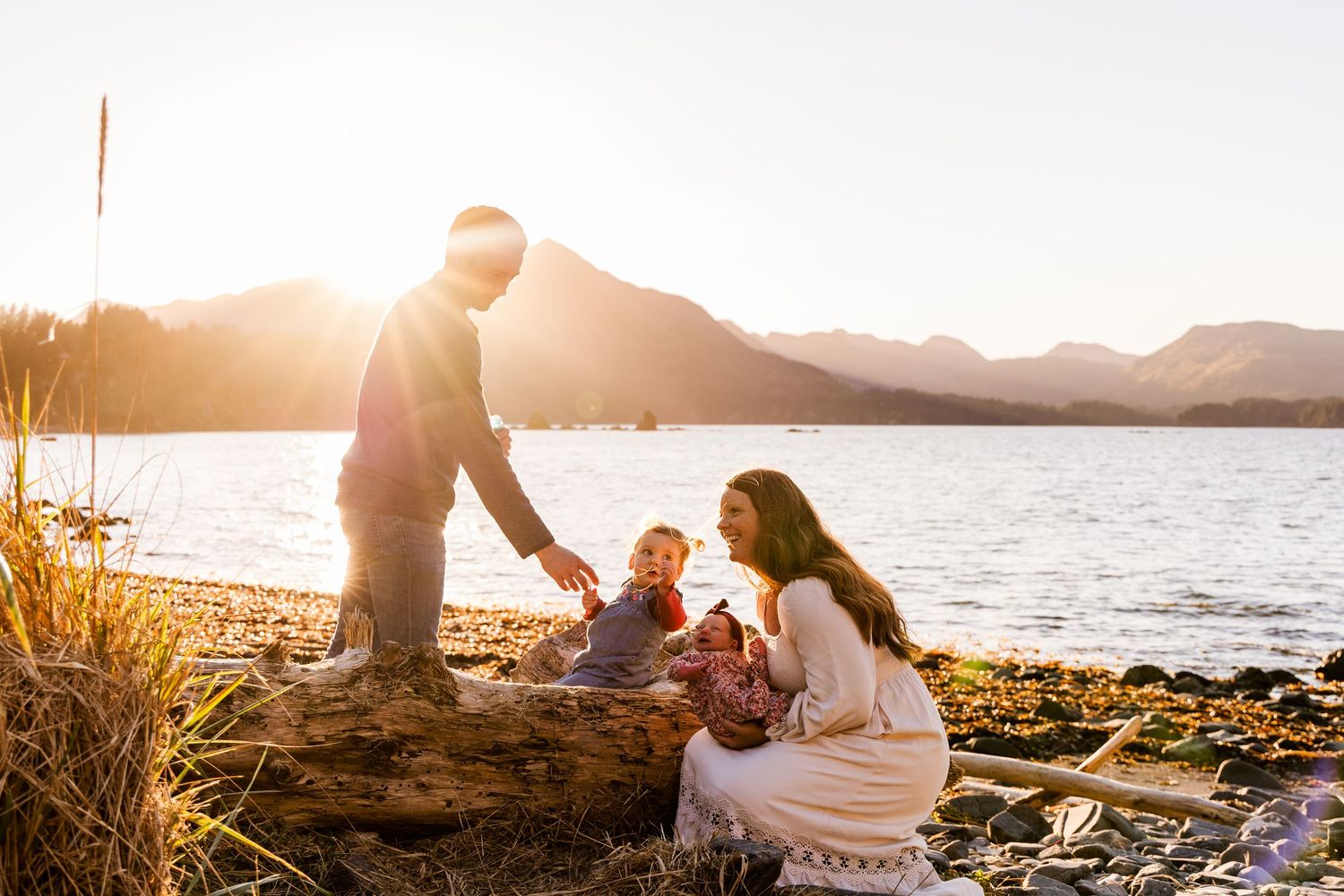 A romantic proposal unfolds along a scenic coastal cliff with mountains and ocean views at golden hour.