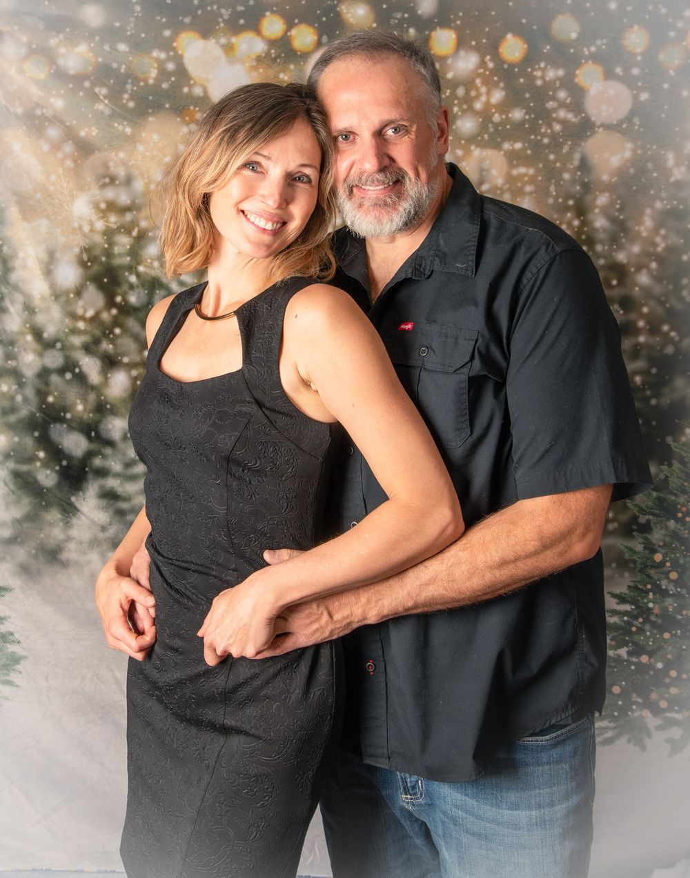 A couple poses together against a sparkly bokeh background in a romantic holiday portrait.