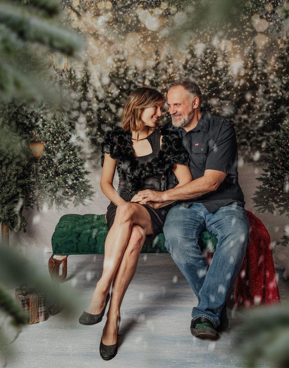 Romantic couple sitting together on a bench surrounded by dreamy holiday decorations and twinkling lights.