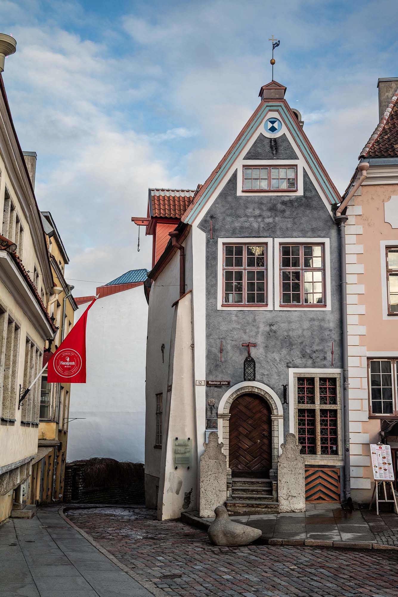 Historic cobblestone alley with traditional medieval buildings and steep stairs in Tallinn's Old Town, Estonia.