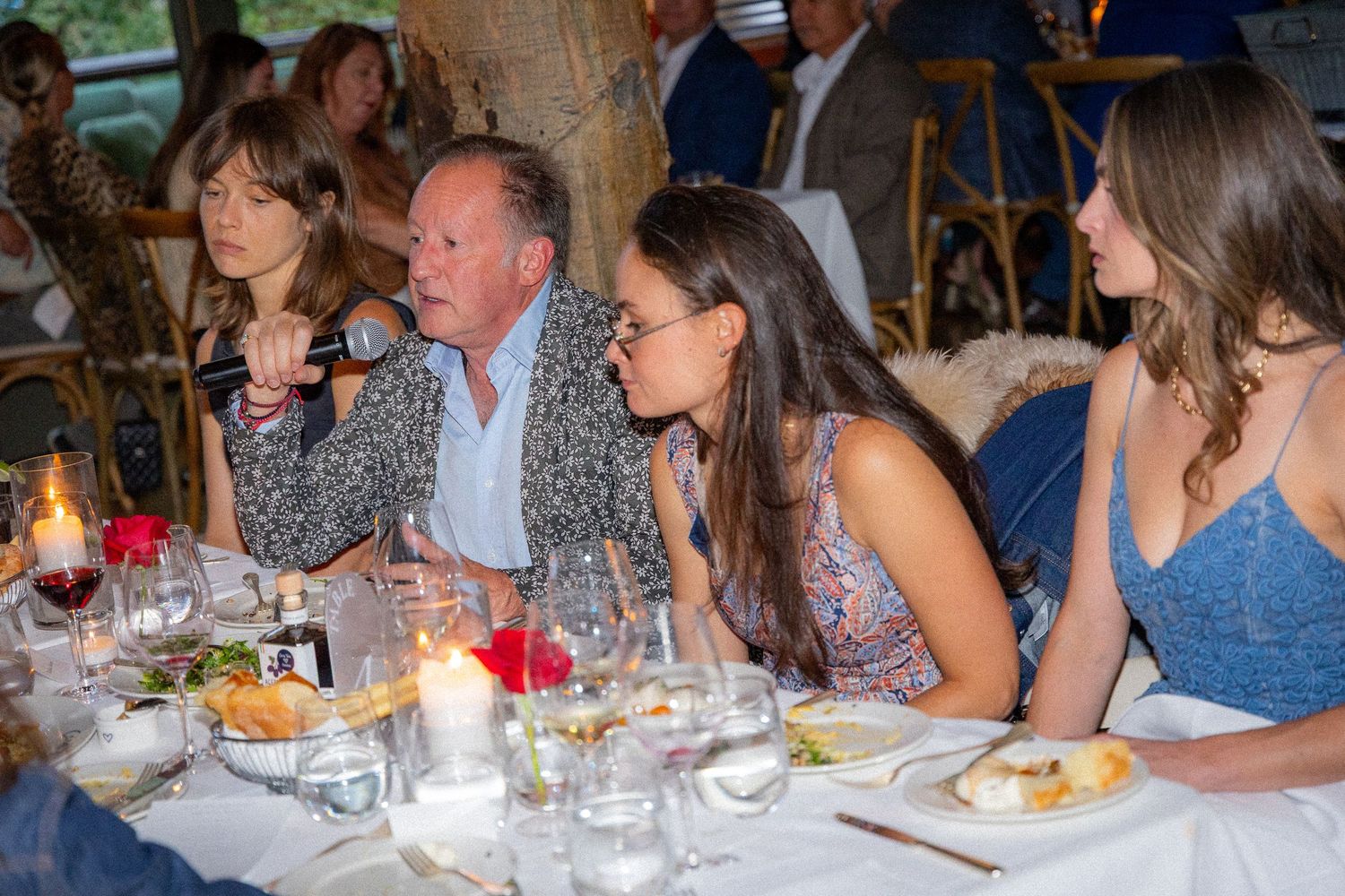 A group of people enjoying dinner and conversation at a long table in a restaurant setting.