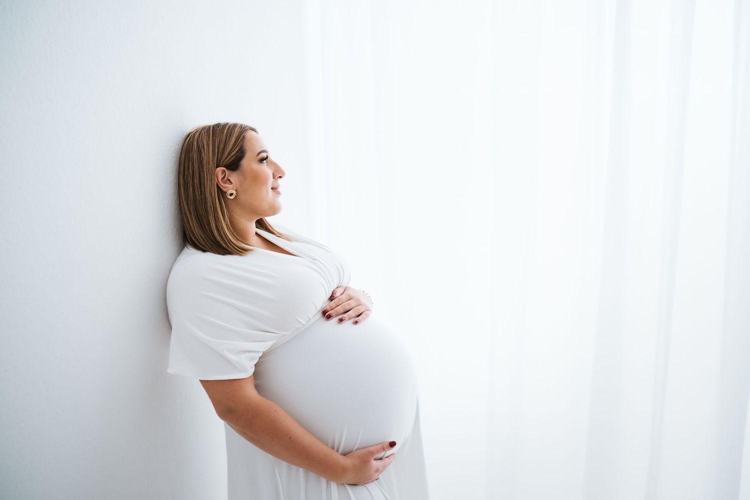 Side view maternity portraits in white showing different stages of pregnancy.