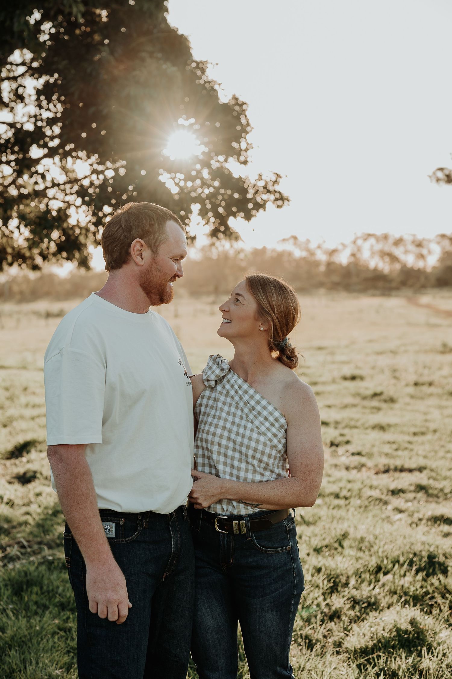 Couple sharing intimate moment in golden sunset light on grassy hillside in bororen.