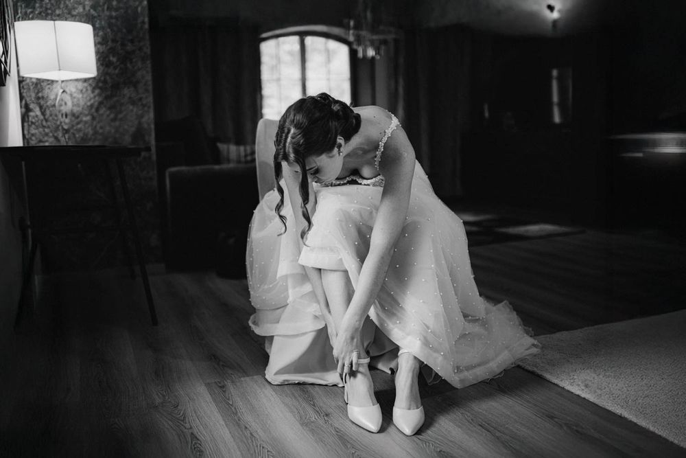 Černobílá fotografie nevěsty při obouvání svatebních bot – Hotel & Garden U Holubů - Čeladná.