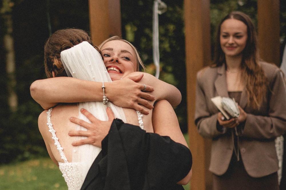 Radostné objetí nevěsty a svatební hostky po obřadu – Hotel & Garden U Holubů - Čeladná. Svatební fotograf Jiří Tulach.