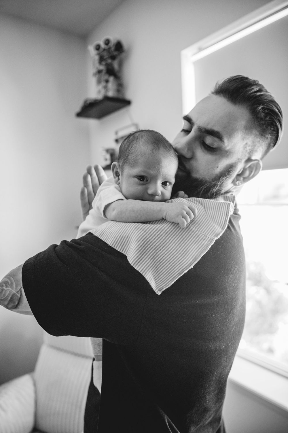 A parent holds and comforts their sleeping baby in a tender embrace shown across four similar black and white photos.