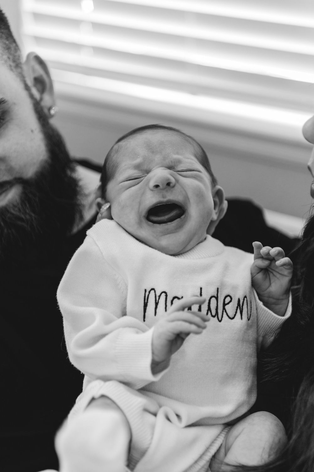 A series of black and white photos showing a laughing baby wearing a white onesie.