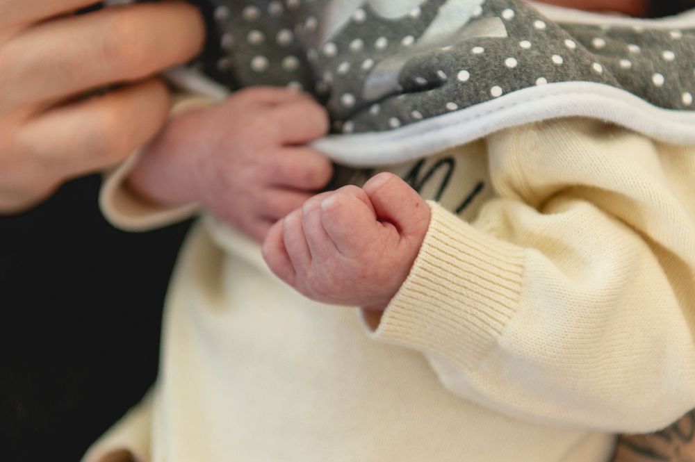 A person's hands fold a soft white fabric or towel in a sequence of detailed steps.