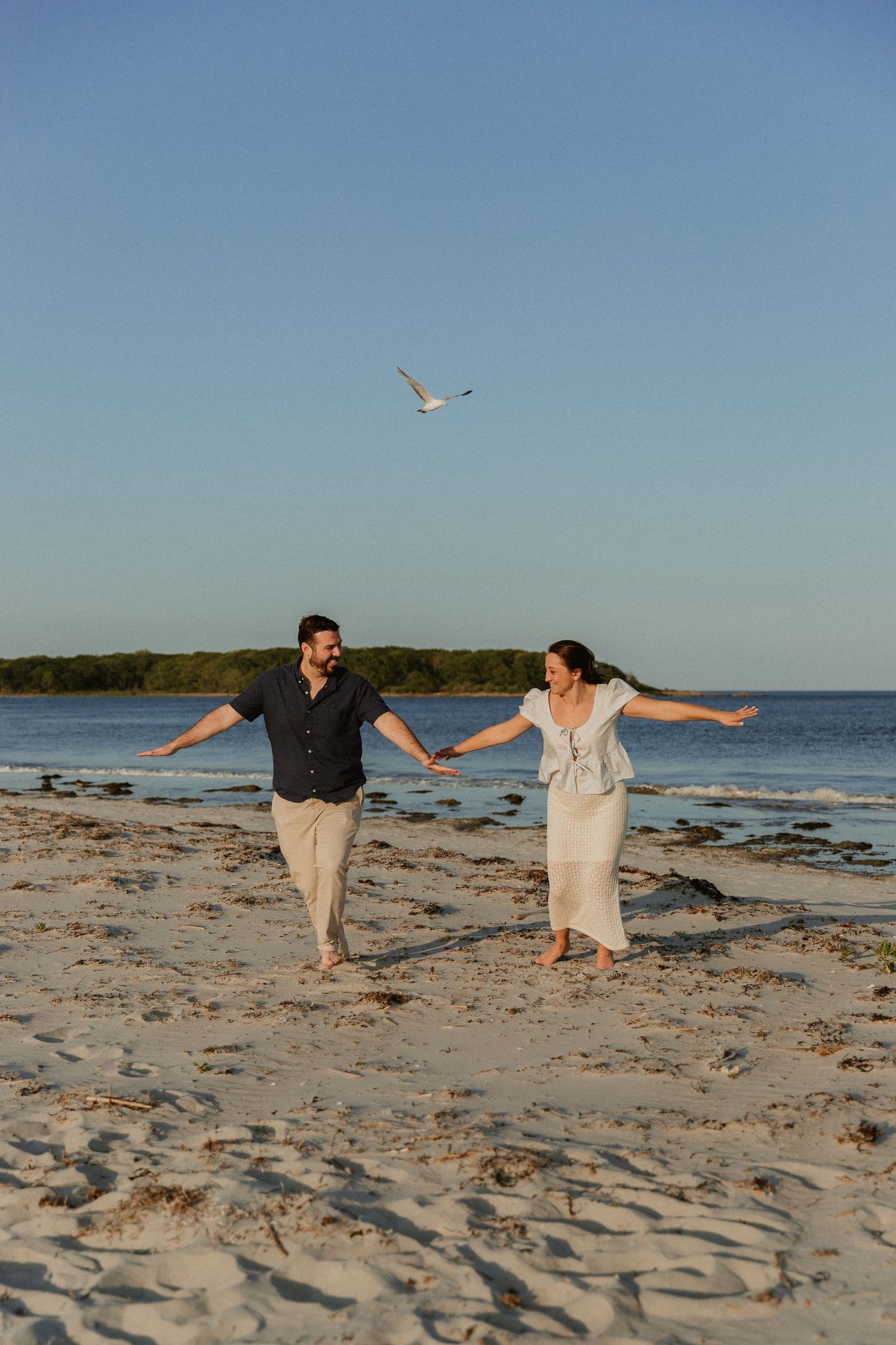 People holding hands and spinning together on a sandy beach at sunset.