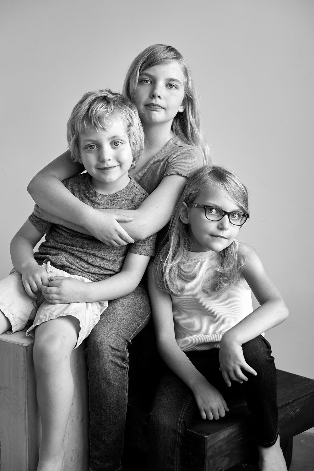 Black and white portrait series showing playful siblings hugging and interacting on a couch.
