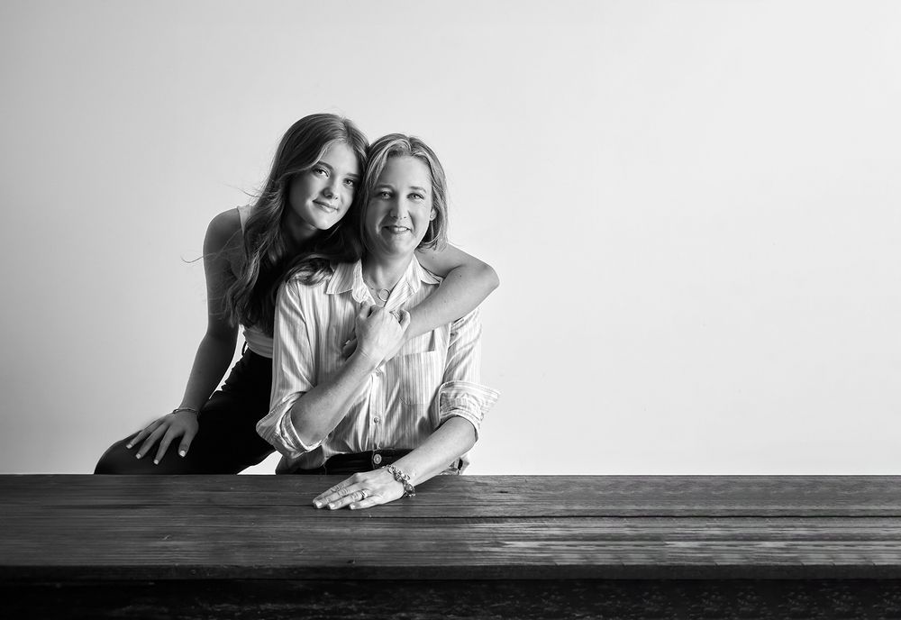 Black and white portrait of two people sitting together on wooden surface.